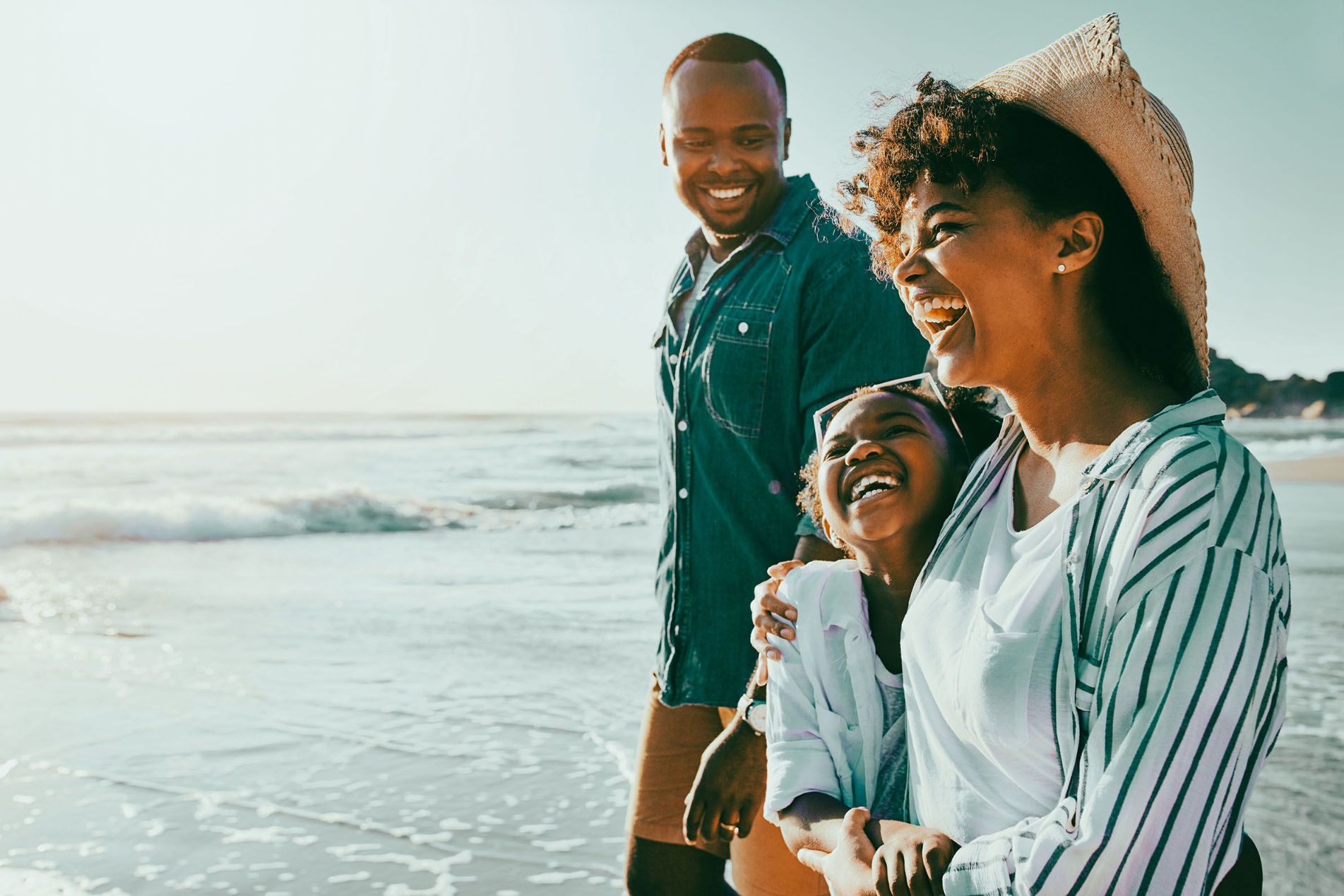 A family of three laughing together on a beach